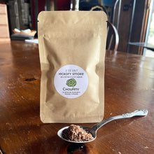 Load image into Gallery viewer, ChouAmi Hickory Smoke Salt 2oz kraft pouch with a spoonful of smoked sea salt on a wooden table.