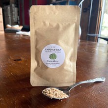 Load image into Gallery viewer, ChouAmi Chipotle Salt 2oz kraft pouch with a spoonful of chipotle-pepper sea salt on a wooden table.