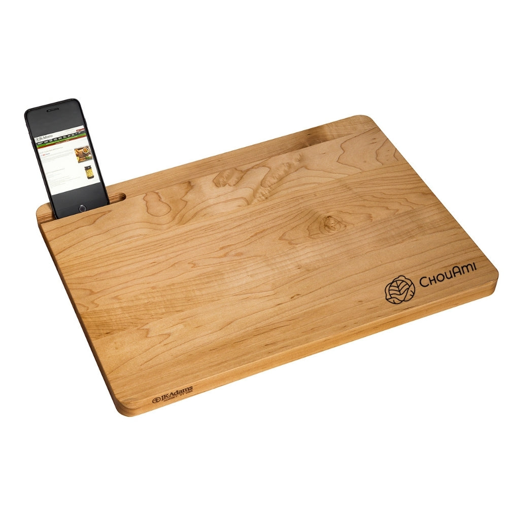 A maple wood cutting board being used to chop vegetables.