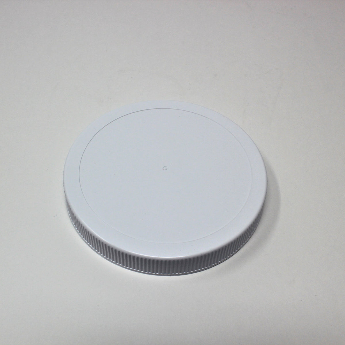 Single white plastic Le Parfait Familia Wiss screw-top lid, angled view on a gray background.