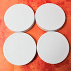 Four white plastic Le Parfait Familia Wiss screw-top lids, top-down on an orange watercolor background.