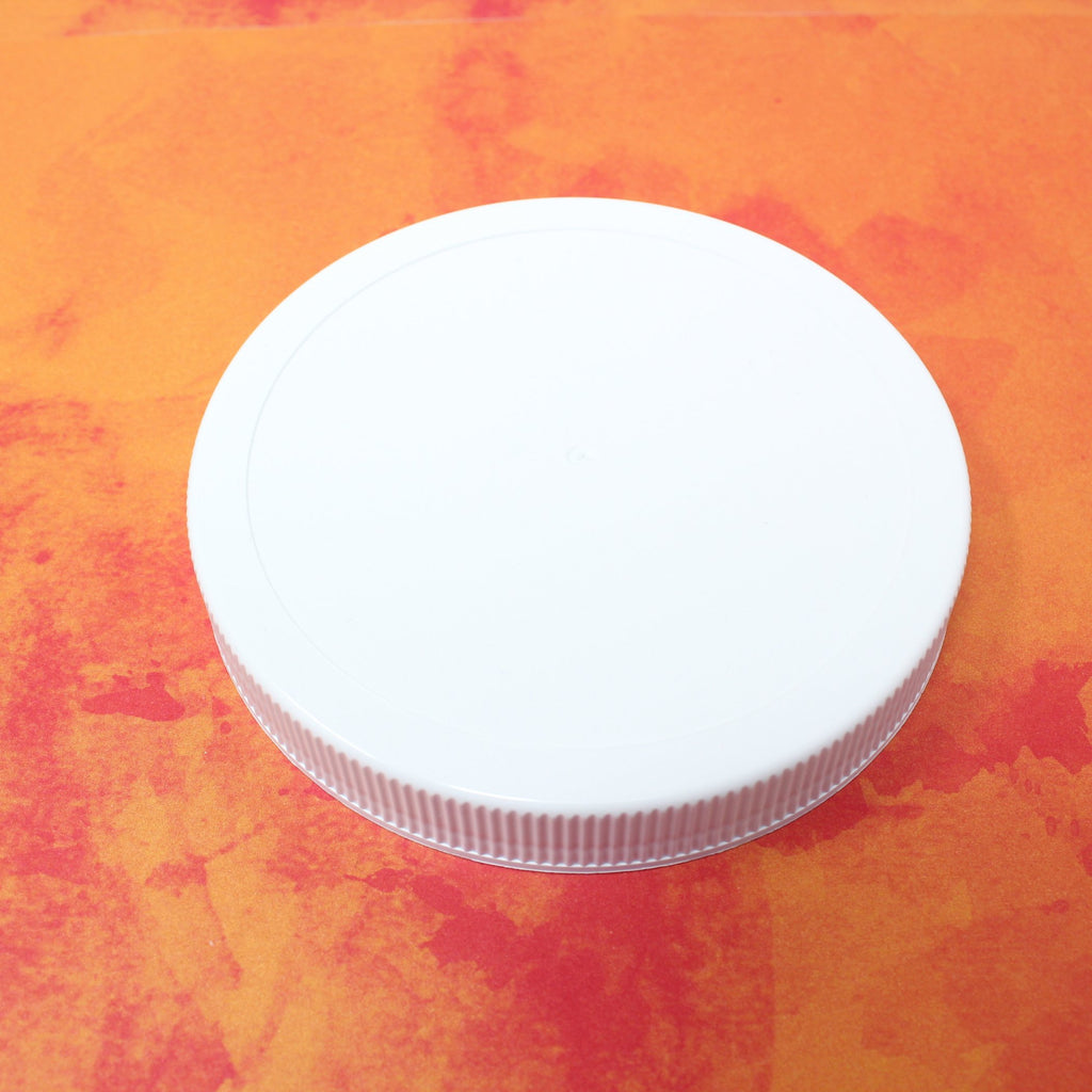 Single white plastic Le Parfait Familia Wiss screw-top lid, angled view on an orange watercolor background.