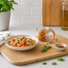 Load image into Gallery viewer, Le Parfait Bistrot Jar of dried fusilli on a cutting board beside a plate of cooked tomato pasta with basil and olive oil.