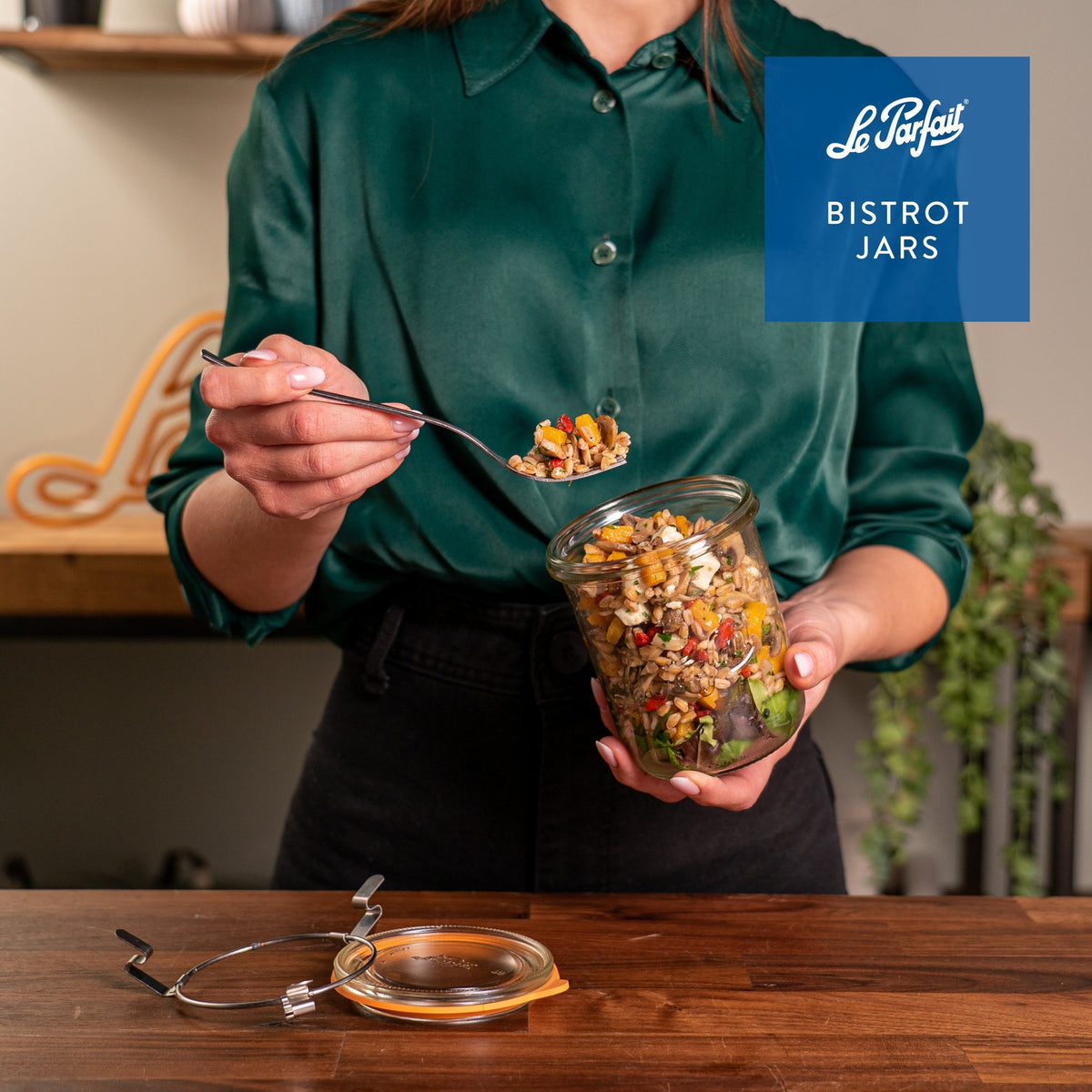 Le Parfait Bistrot Jars product card - woman in green silk shirt holding a clip-top jar of grain-and-vegetable salad with a fork.