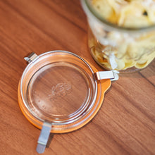 Load image into Gallery viewer, Open Le Parfait Bistrot jar lid with orange gasket and wire bail clamps on a wooden table, tortellini-filled jar behind.