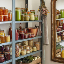 Load image into Gallery viewer, Pantry shelves stocked with Le Parfait jars and bottles of preserves and juices, with a copper bowl, vintage gold mirror, and dried flowers.