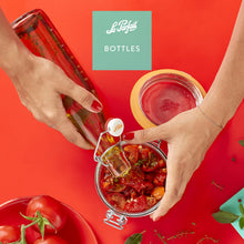 Load image into Gallery viewer, Le Parfait Bottles product card - hand pouring olive oil from a swing-top bottle into an open hermetic jar of sun-dried tomatoes.