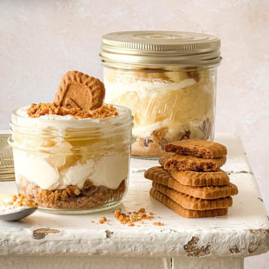 Banoffee dessert layered in a small Le Parfait Familia Wiss terrine beside a larger filled terrine and a stack of caramelized cookies.