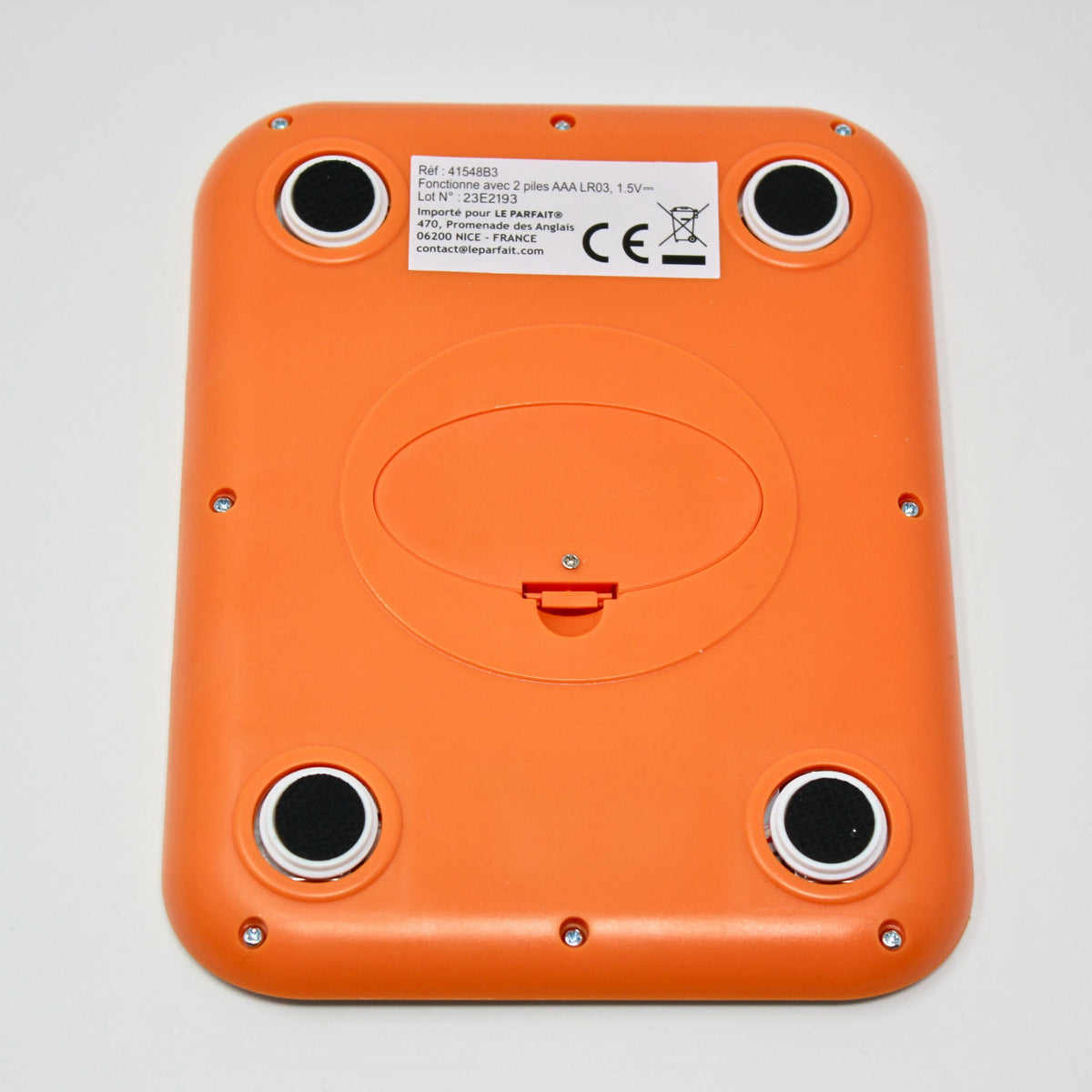 Bottom of the Le Parfait kitchen scale showing orange plastic underside, battery compartment, and rubber feet.