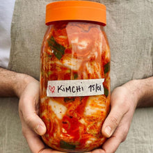Load image into Gallery viewer, Hands holding a Le Parfait Screw Top Jar of fermenting kimchi labeled 'KIMCHI' on masking tape.
