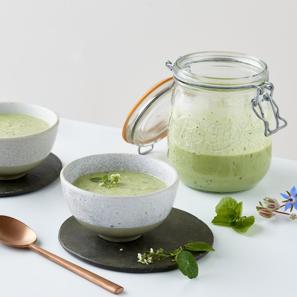 Le Parfait Super Jar of green herb soup beside two ceramic bowls filled and garnished with mint and borage flowers.