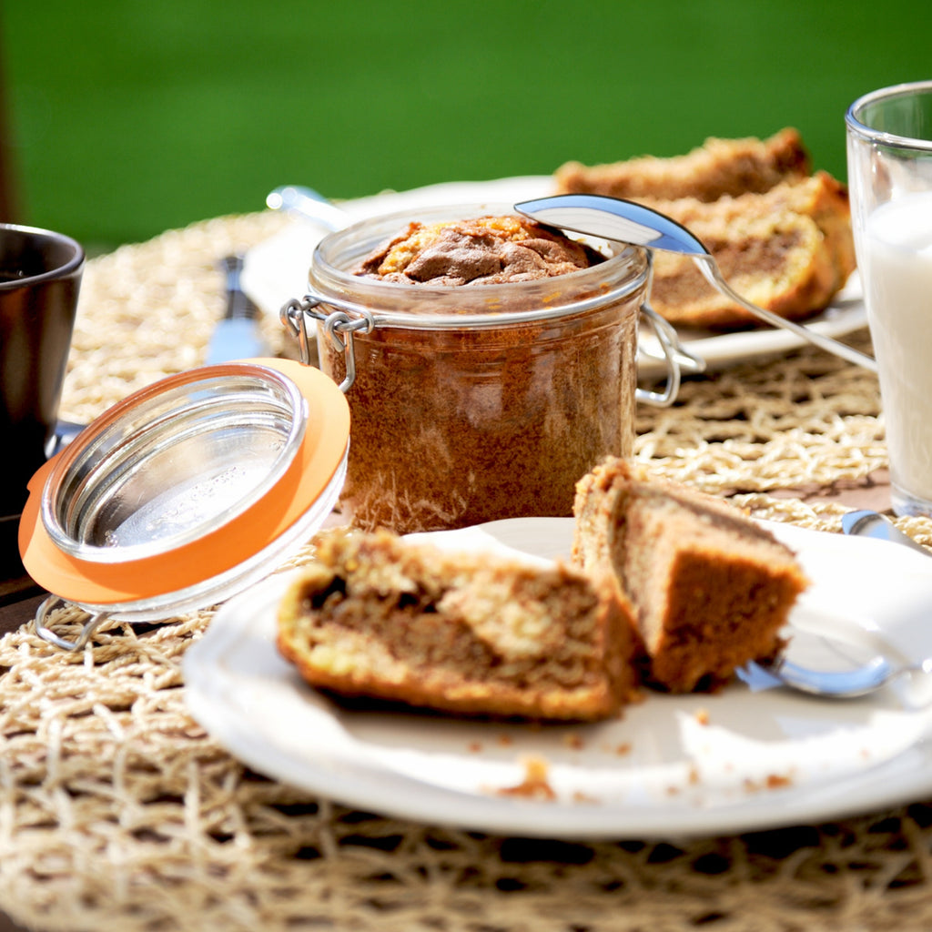 Le Parfait Super Terrine of cinnamon bread pudding on an outdoor picnic table with a glass of milk and slices on a plate.