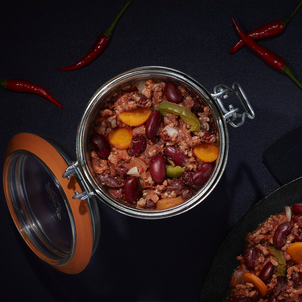Top-down Le Parfait Super Terrine of chili con carne with red kidney beans, ground beef, peppers, and red chiles on a dark surface.