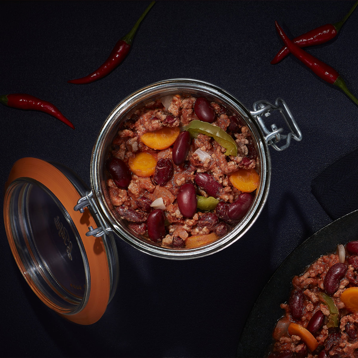 Top-down Le Parfait Super Terrine of chili con carne with red kidney beans, ground beef, peppers, and red chiles on a dark surface.