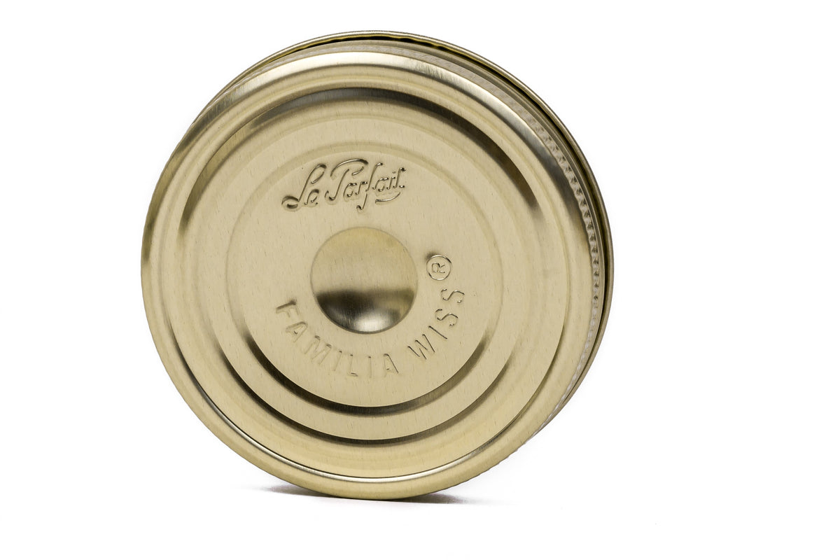 Single gold Le Parfait Familia Wiss metal canning lid, angled side view on white.
