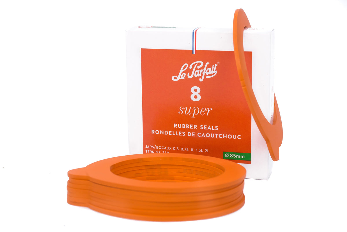 8-pack box of 85mm Le Parfait Super rubber seals beside a stack of orange replacement gaskets for 350ml terrines and 500ml–2L jars.