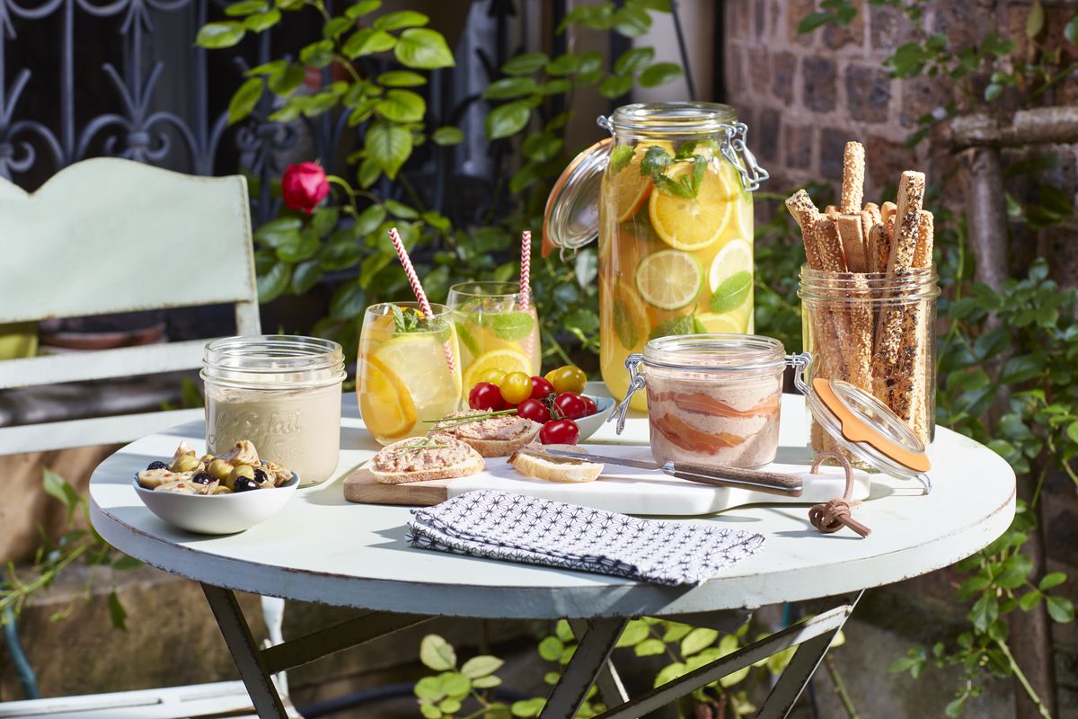 An outdoor aperitif table set with Le Parfait jars of dips, breadsticks, and lemonade